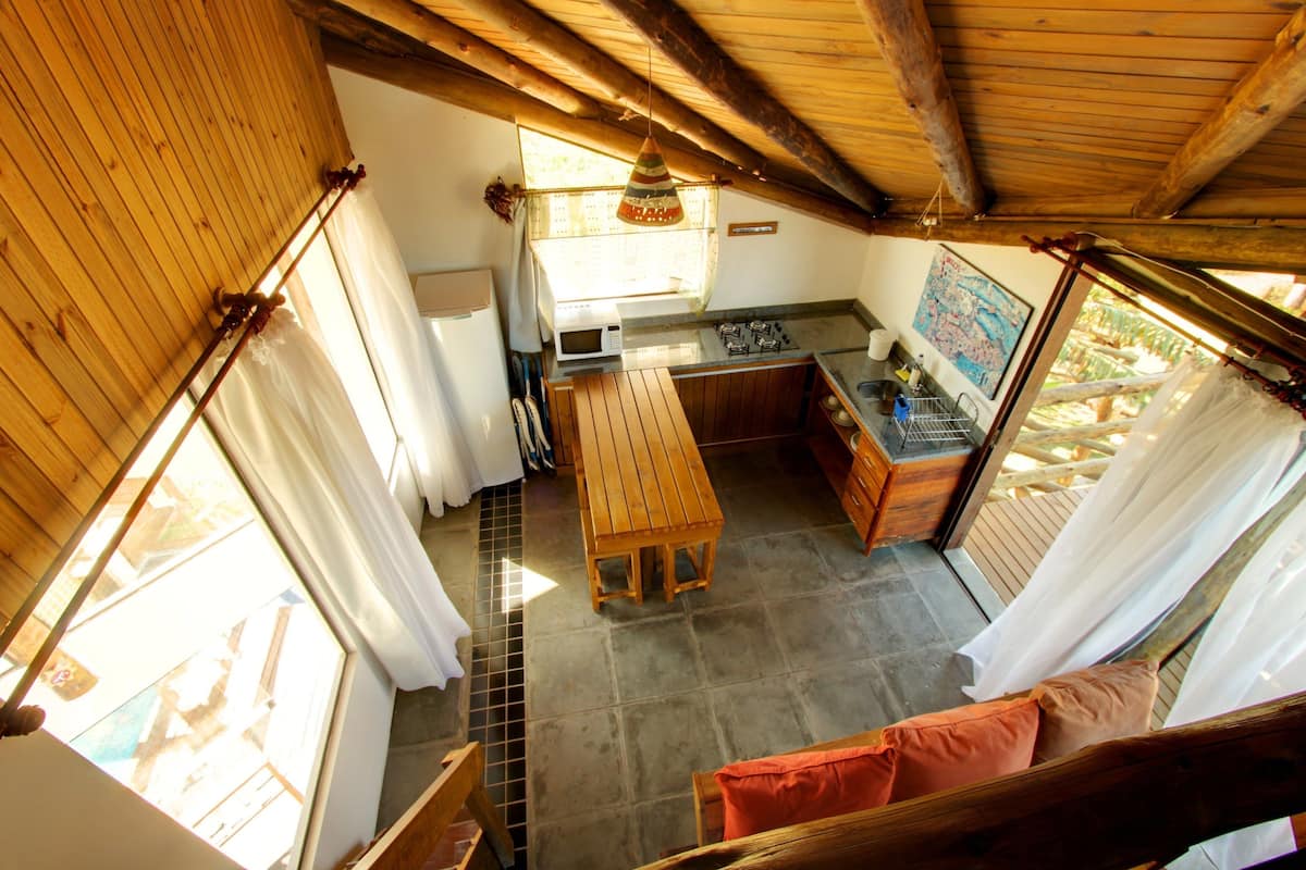 Una cocina rústica con techo de madera, una mesa de comedor y vistas al exterior.