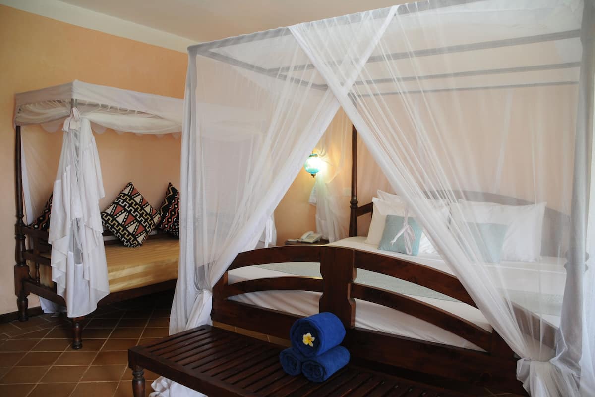 A room with two wooden beds, each with a canopy bedspread and pillows.
