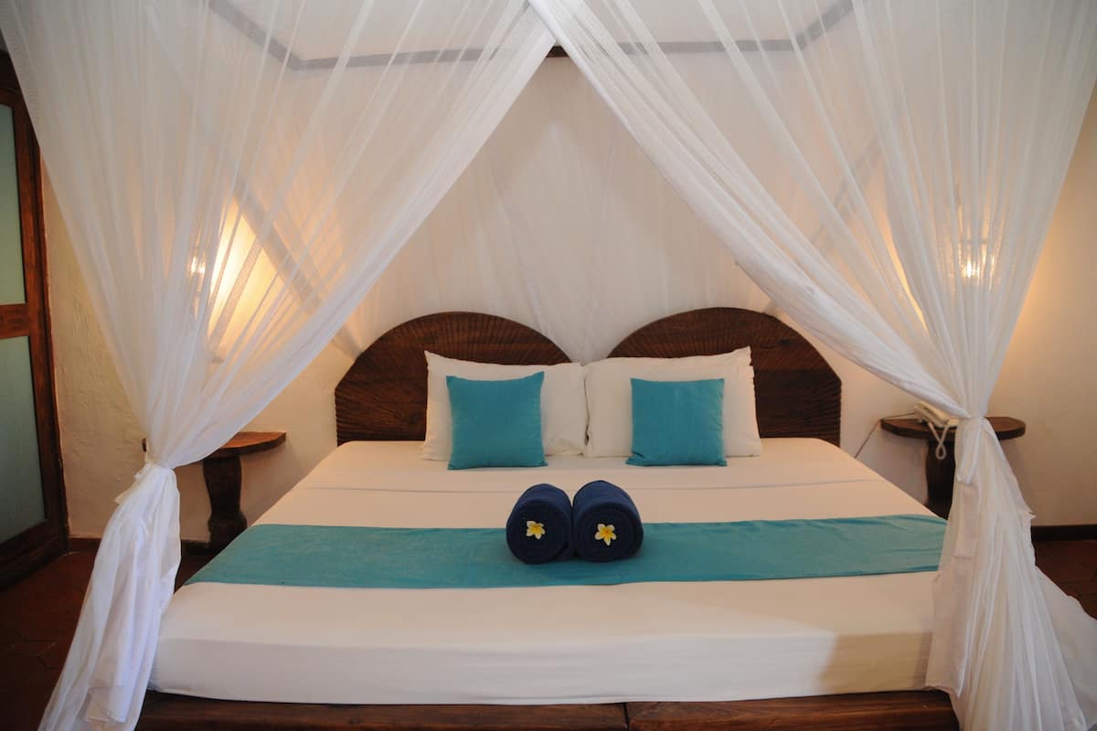 A bed with a canopy, two pillows, and a bedside table.