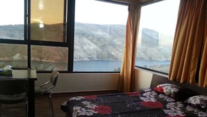 Habitación de hotel con una cama grande, una mesa de comedor y vistas a un paisaje montañoso.