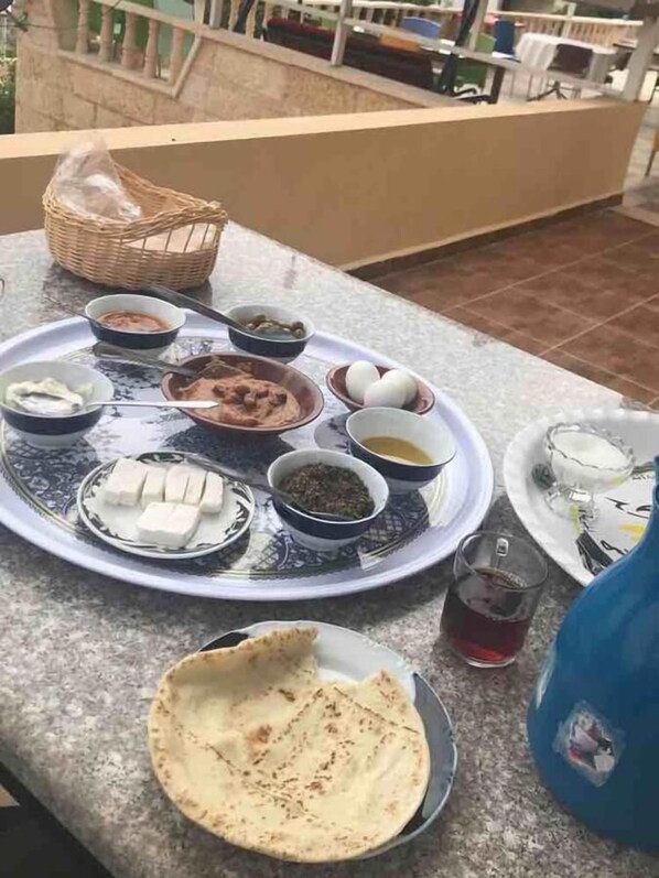Una mesa de comedor con diversos platos, incluyendo pan plano, huevos y recipientes con salsas.