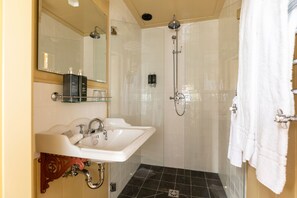 Bathroom features a dual sink vanity, large mirror, and glass-enclosed shower area.