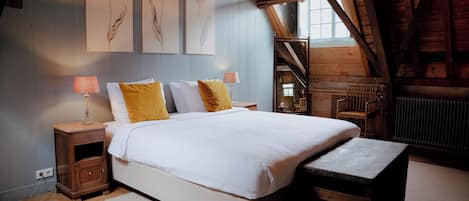 A bedroom with a large bed, wooden headboard, a nightstand with a lamp, and a bench.