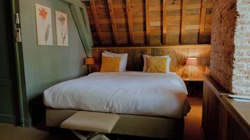 A bedroom with a wooden ceiling, a bed with white bedding, two bedside lamps, and a bench at the foot of the bed.