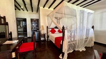 Une chambre avec un lit sous un dais, un bureau en bois et une chaise.