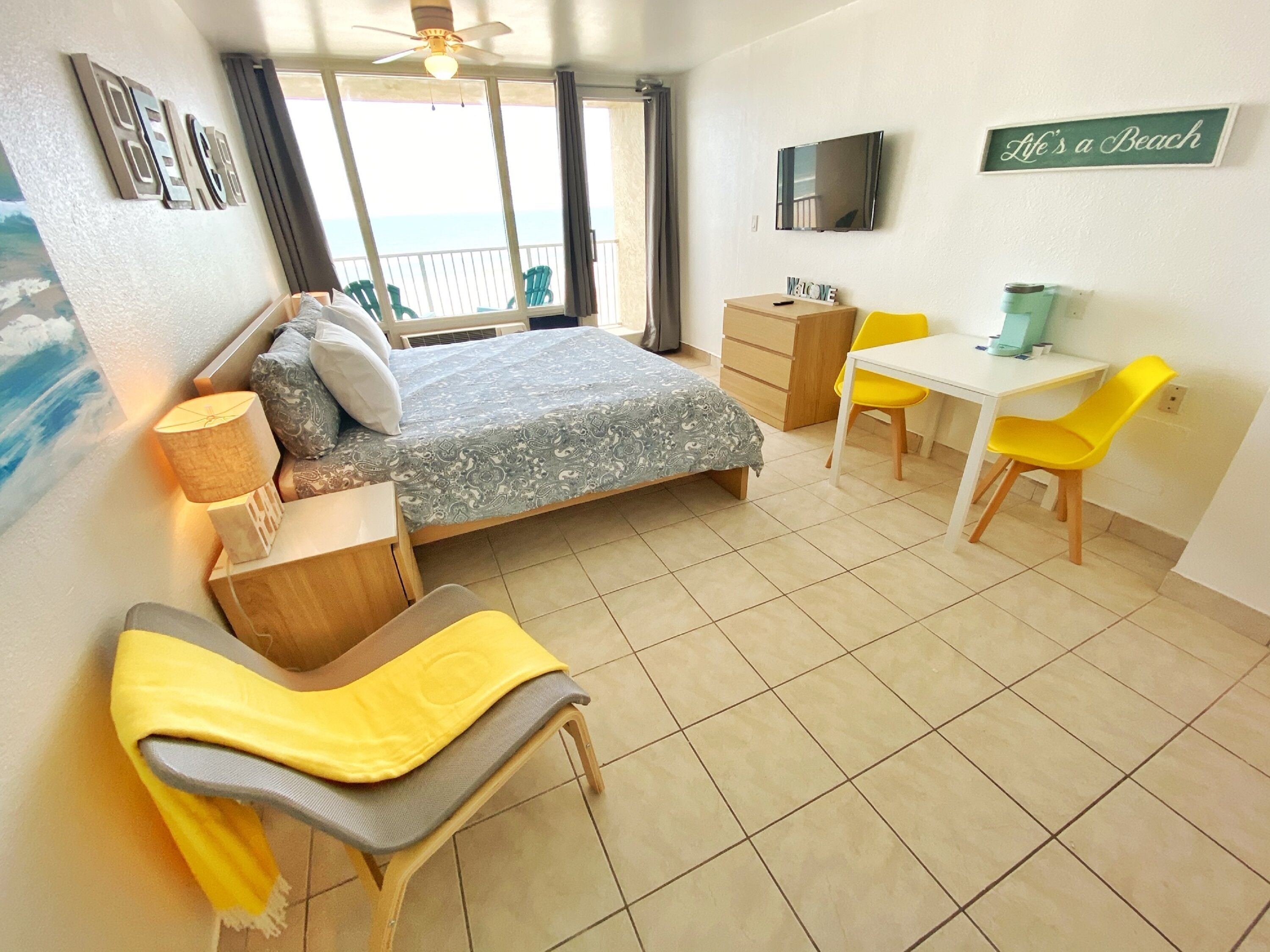Une chambre à coucher comprenant un lit, une table de chevet, une chaise, un bureau et une vue sur la mer.