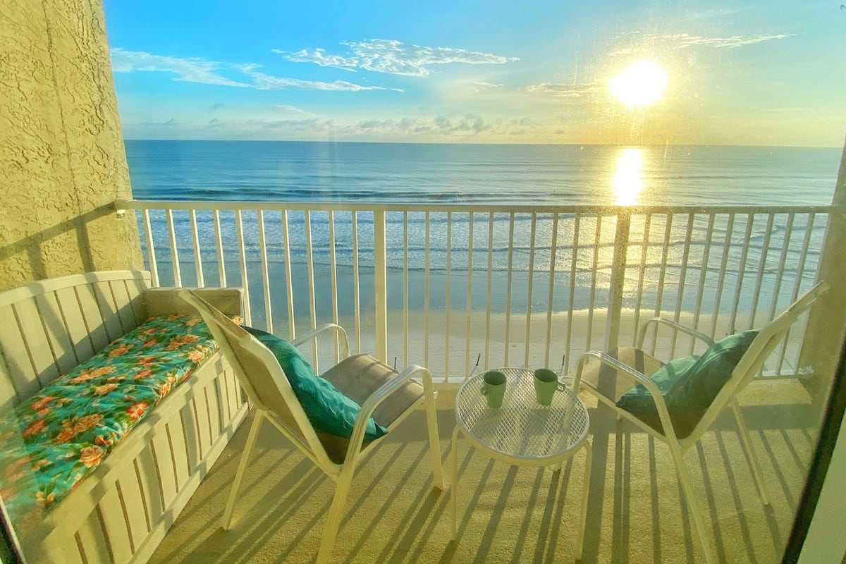A balcony with a view of the ocean and a sunset.
