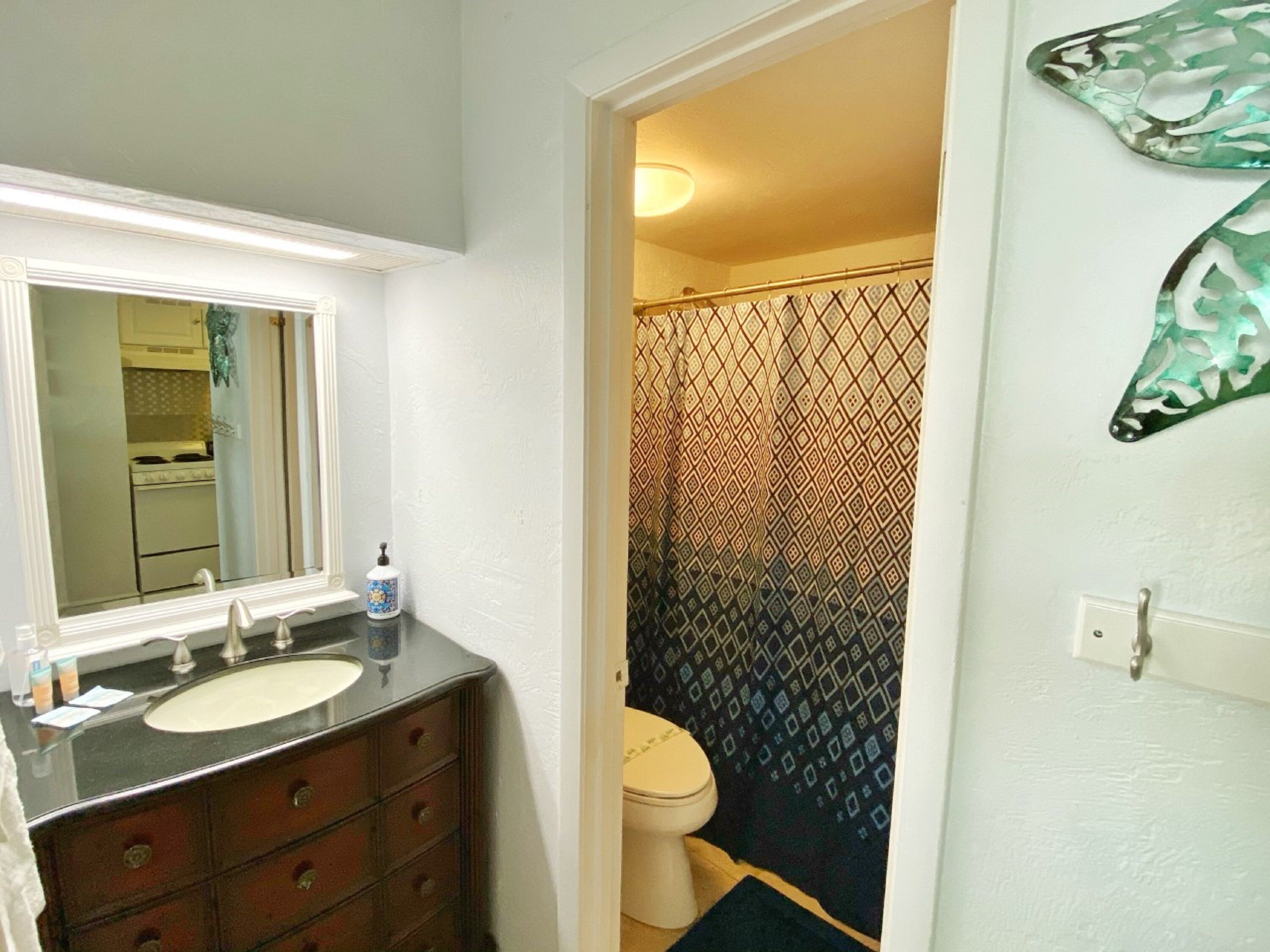 A bathroom with a white sink, dark wooden vanity, and a patterned shower curtain.