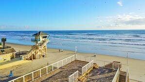 A beach with a lifeguard tower, wooden boardwalk, and a clear view of the ocean.