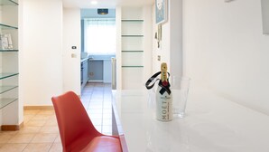 Uma cozinha moderna com armário de vidro, uma cadeira vermelha e uma garrafa de champanhe Moët em uma bancada branca.