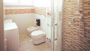 Een badkamer met toilet, bidet en douchehoek.
