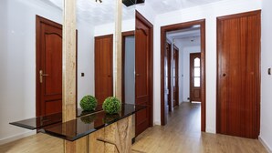 A hallway with wooden doors, a glass-top table, and a small green plant. - SOBREMAR Apartment - STUNNING Views (Salou)