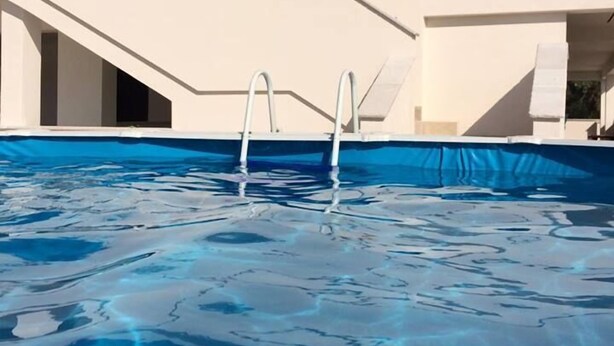 A swimming pool with a modern architectural design, featuring a geometric roof and a clear blue water surface. - Agriturismo La Duchessa e il Contadino (Vieste)