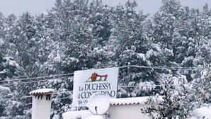 A sign for La Duchessa Il Contadino with a snowy landscape in the background. - Agriturismo La Duchessa e il Contadino (Vieste)