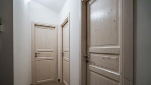 A narrow hallway with wooden doors and a light switch on the wall. - Agriturismo La Duchessa e il Contadino (Vieste)