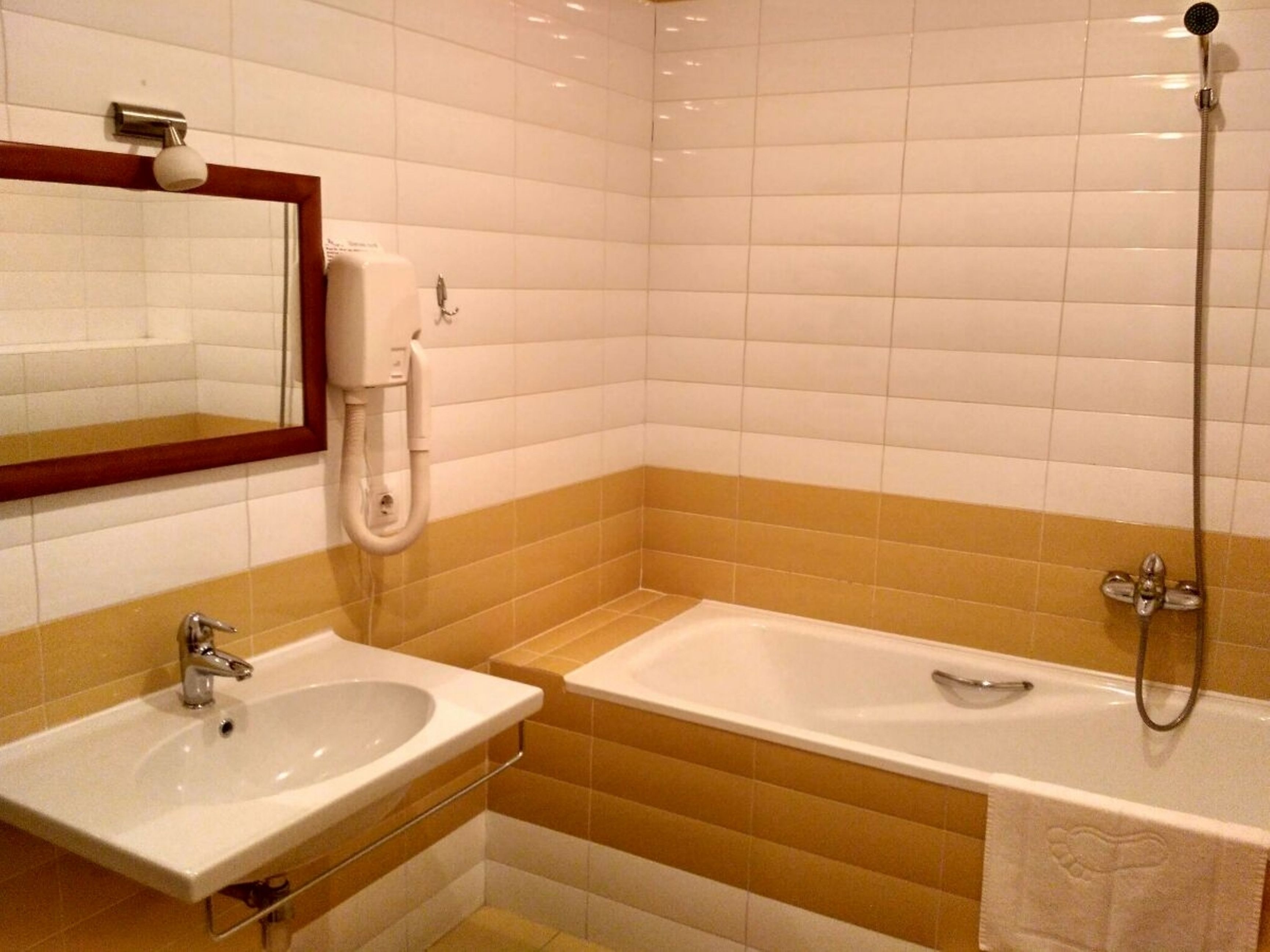 A bathroom with a sink, mirror, and bathtub.