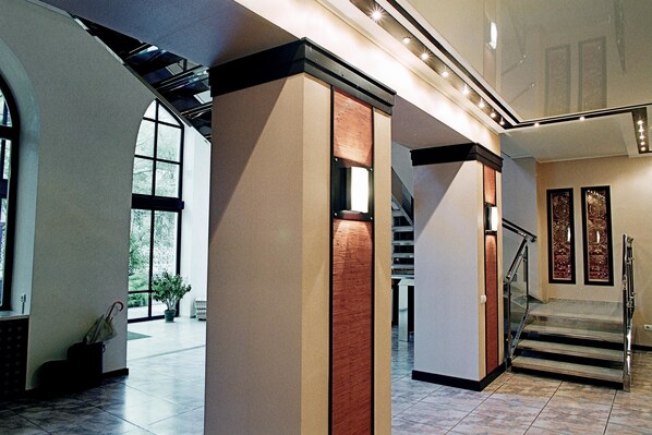 Un vestíbulo amplio con escaleras, ventanas grandes y una planta en maceta.