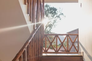 Una escalera de madera que lleva a un balcón con vista a una montaña y árboles.