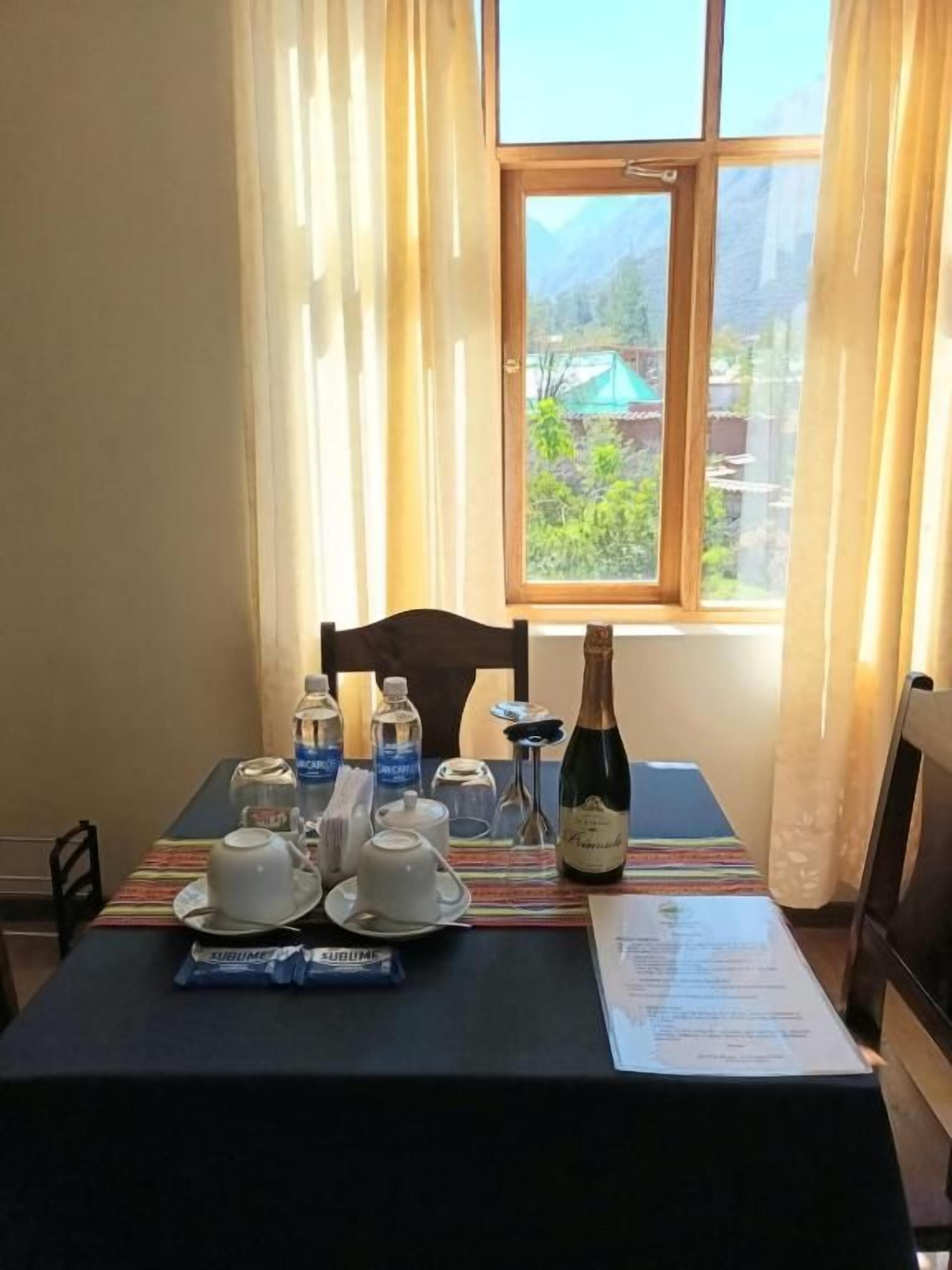 A table set with a bottle of champagne, two cups, and a menu.