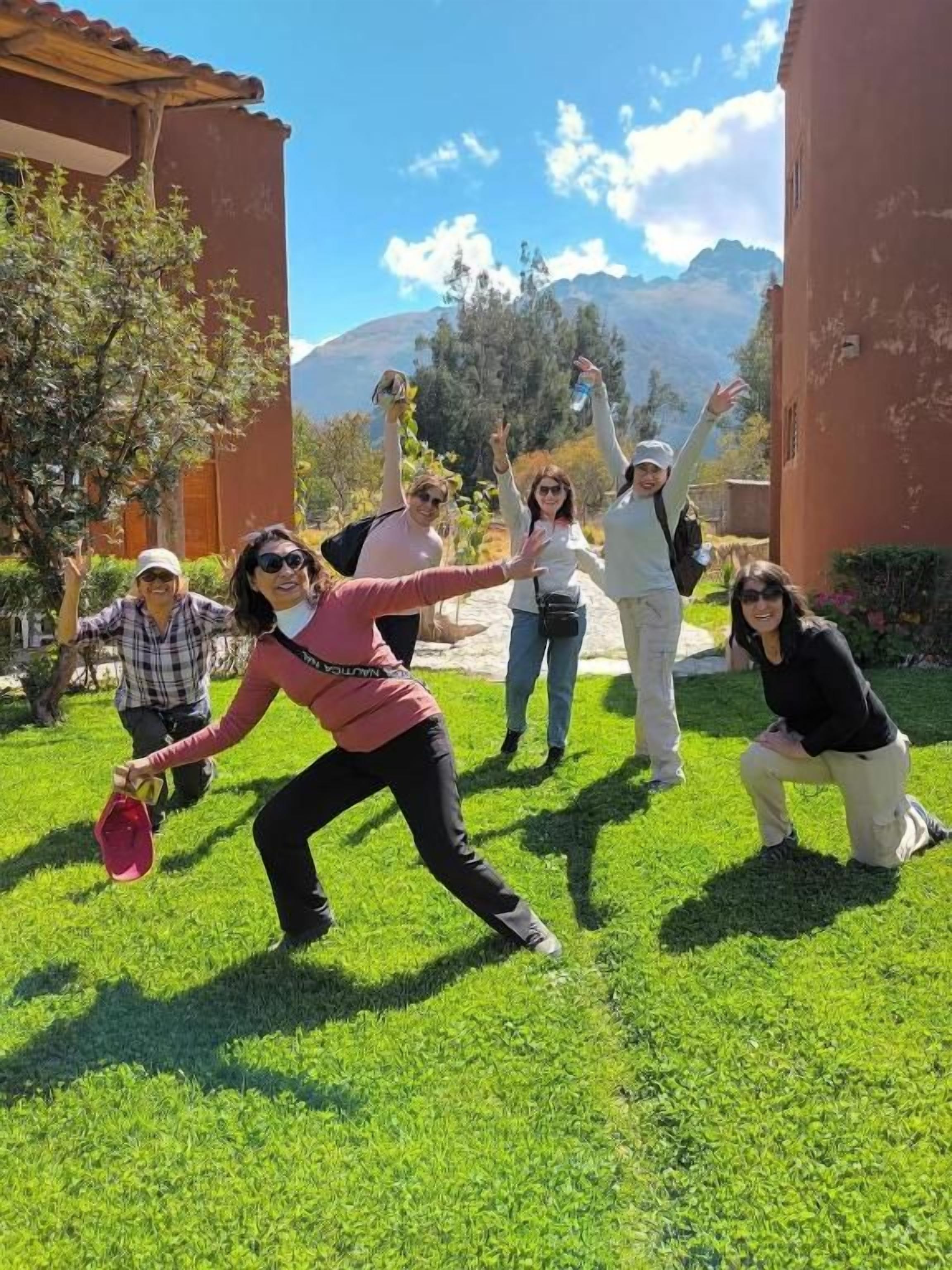 Un grupo de personas al aire libre, con un edificio y montañas al fondo.