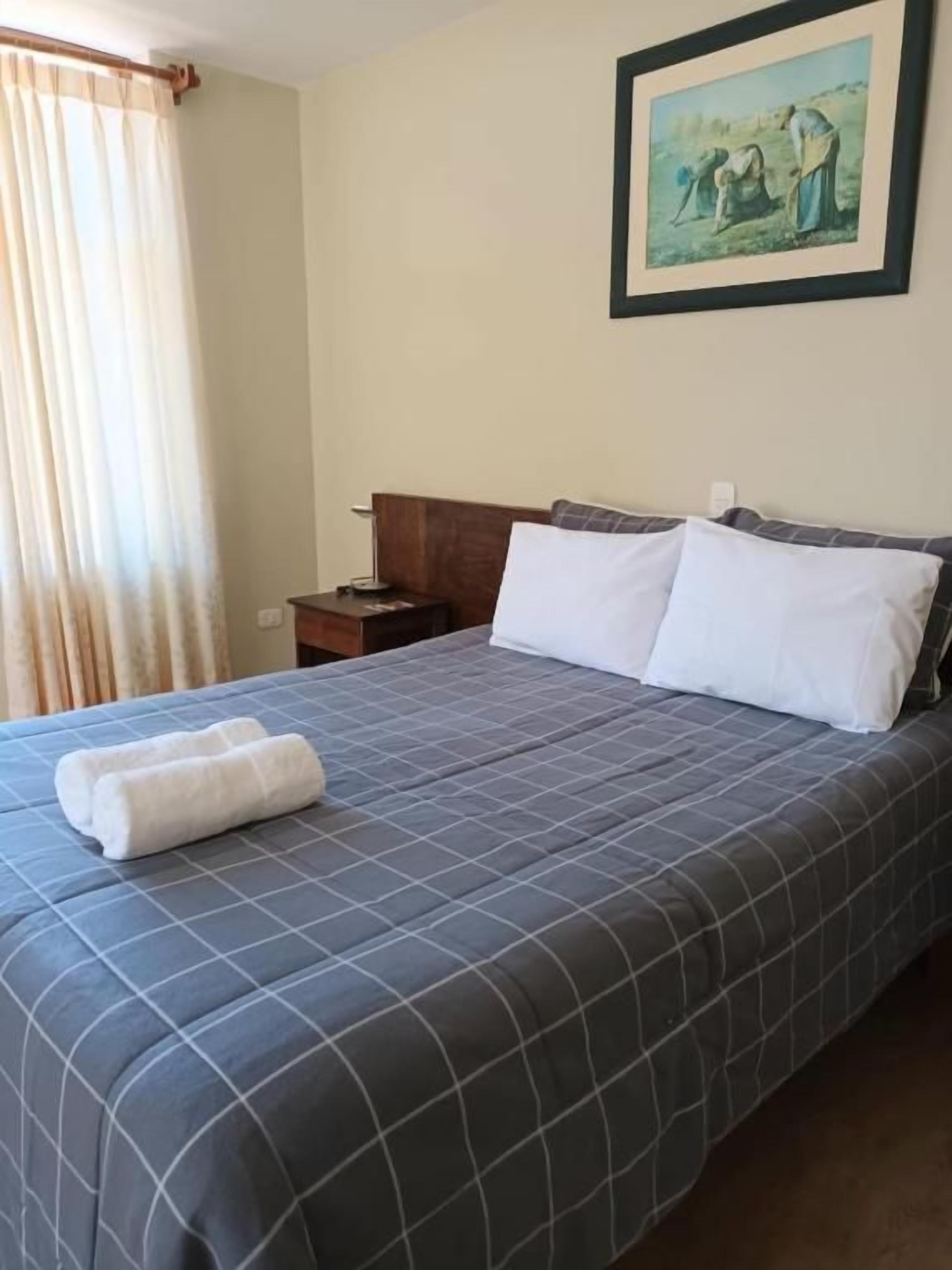 Een hotelkamer met een bed, een nachtkastje en een schilderij aan de muur.