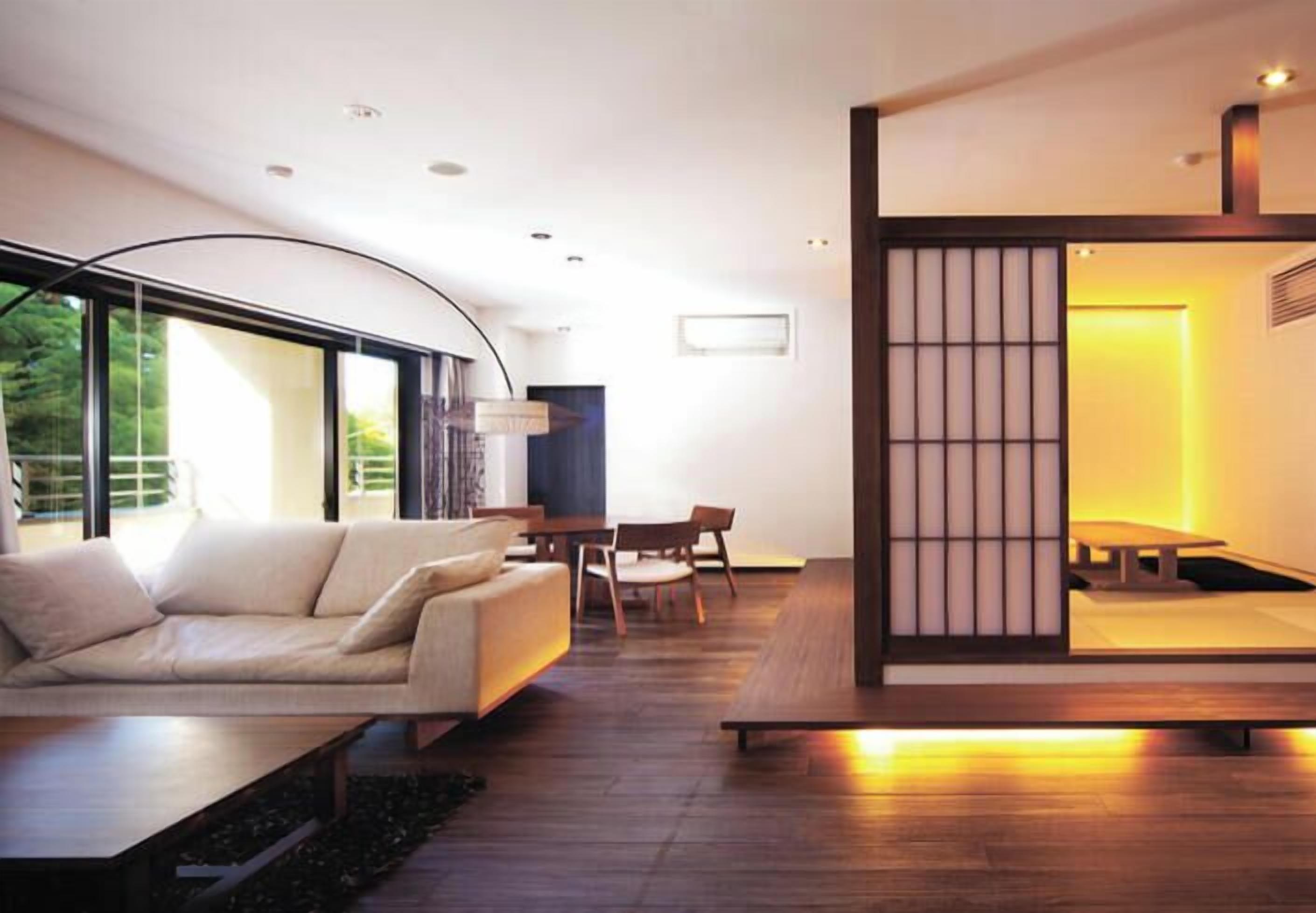 A modern living room with a sofa, dining table, and chairs, large windows, and a traditional Japanese sliding door.