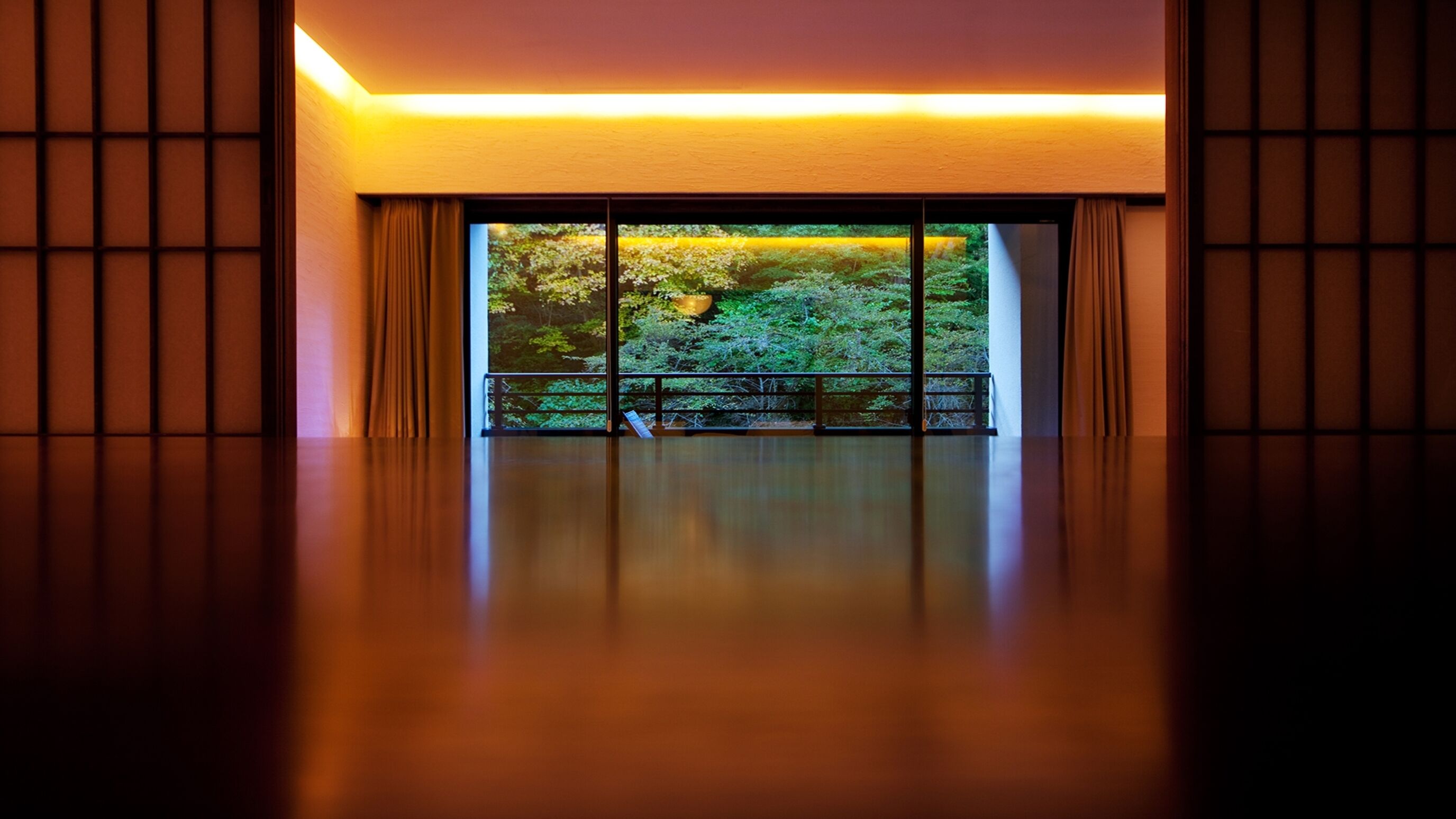 Una habitación con un ventanal grande, suelo de madera y vistas a zonas verdes.