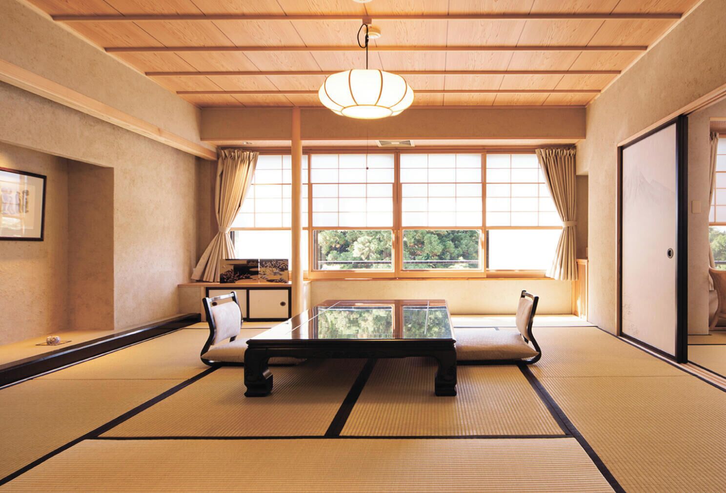 A traditional Japanese room with tatami flooring, a low table, and a hanging light fixture.