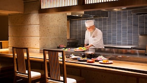 A chef preparing food at a counter with a tiled backsplash and a stove in the background. - Hanare Matsushimakaku (Aizuwakamatsu)
