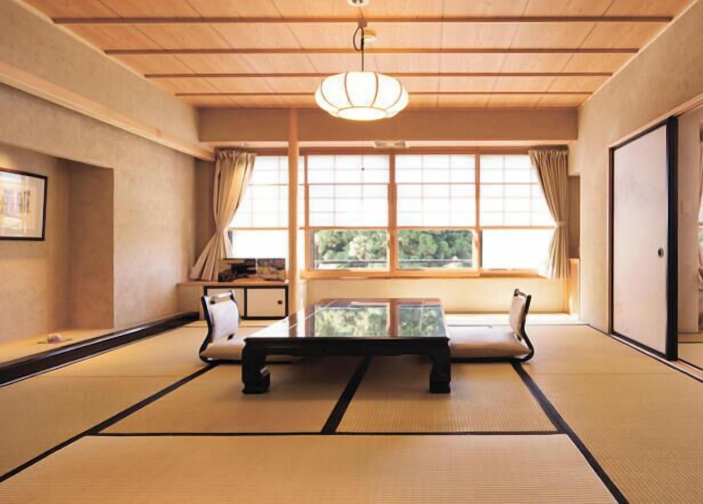 A traditional tatami mat room with a low table, cushions, and a sliding door.