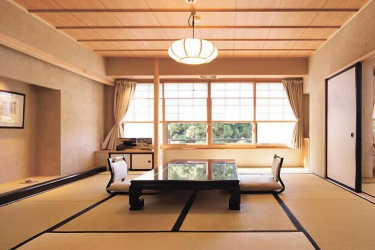 A traditional tatami mat room with a low table, cushions, and a sliding door.
