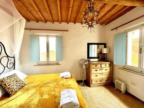 A bedroom with a bed, a dresser, a mirror, a fan, and a radiator. - Huge Family Friendly Villa. Stunning views of Umbria & Tuscany in lovely village (Gioiella)
