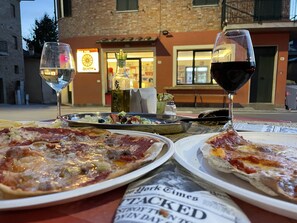 A table with three pizzas, two glasses of wine, and a newspaper. - Huge Family Friendly Villa. Stunning views of Umbria & Tuscany in lovely village (Gioiella)