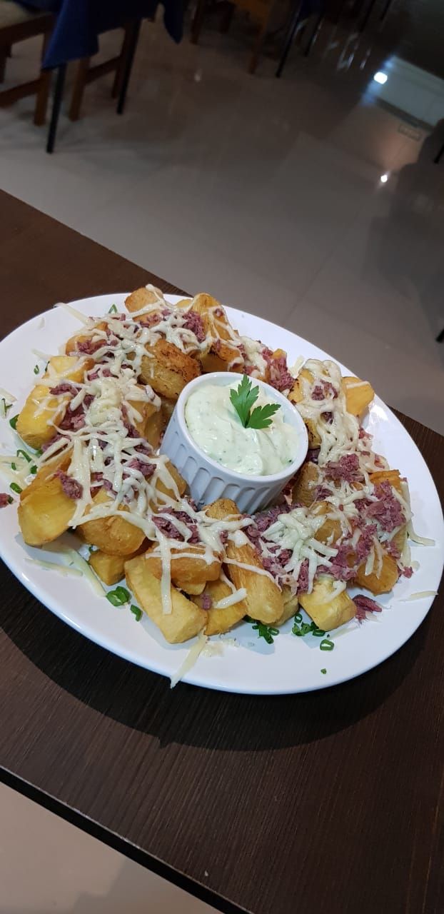A plate of food with a side of dipping sauce and shredded cheese.