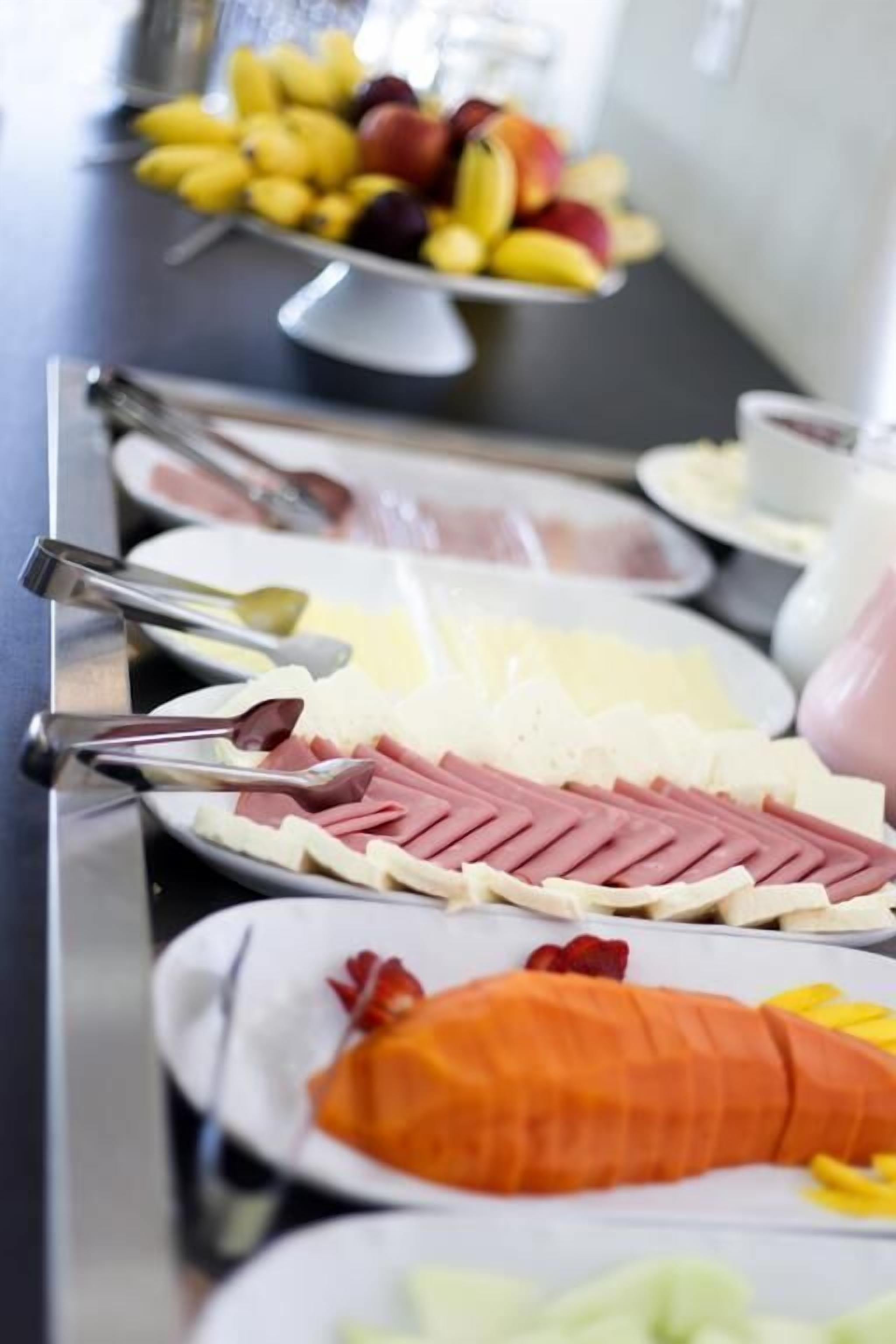 Un bufé con diversos alimentos, incluyendo fiambres, quesos y frutas.