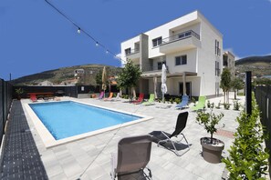 Un bâtiment moderne doté d’une piscine, d’un espace extérieur aménagé et surplombant une colline.