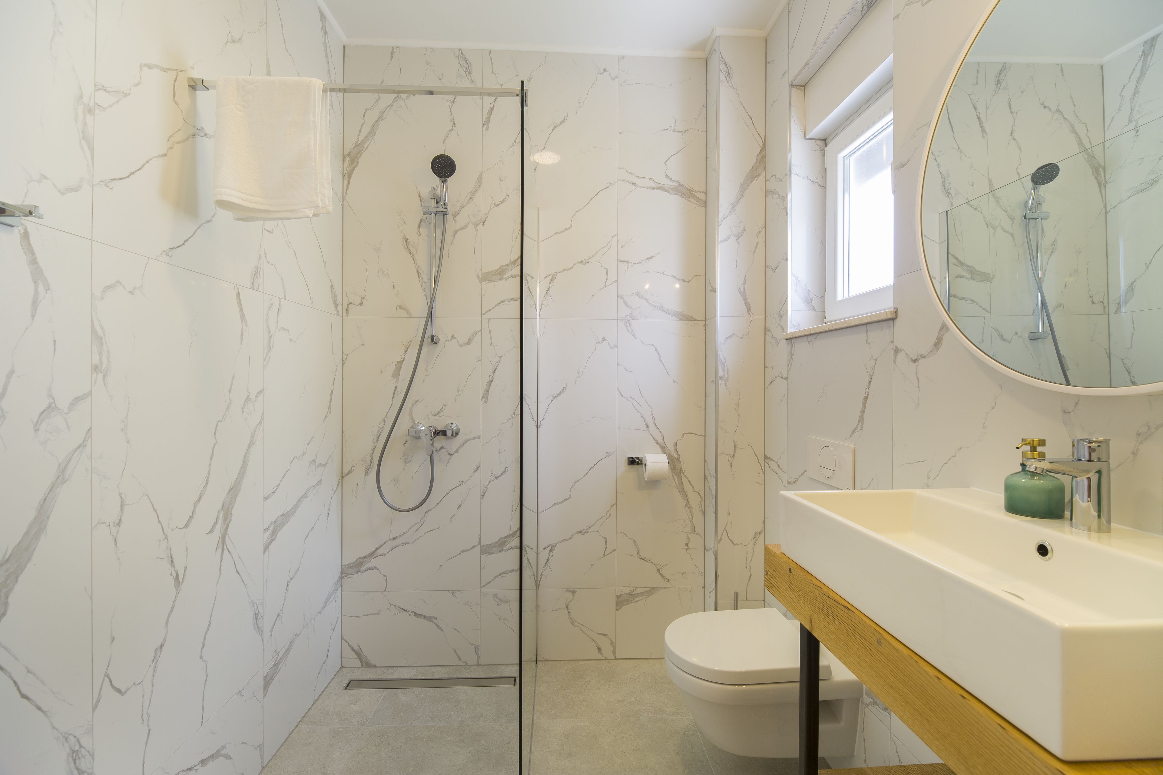 A modern bathroom with a glass shower enclosure, a white toilet, and a sink with a mirror.