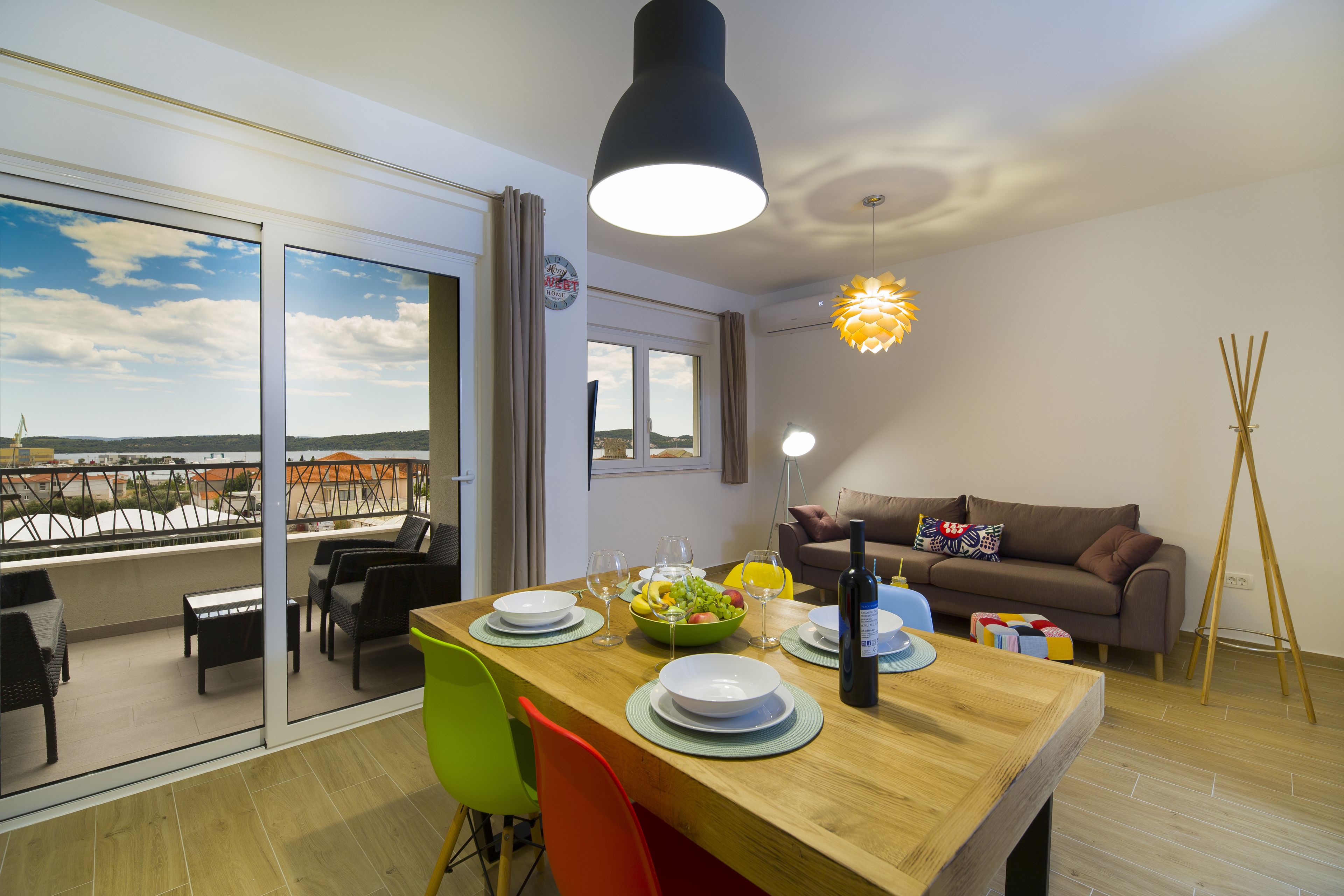 Ein Essbereich mit einem Holztisch, gedeckt für vier Personen, einer Couch und Blick auf die Stadt durch große Fenster.