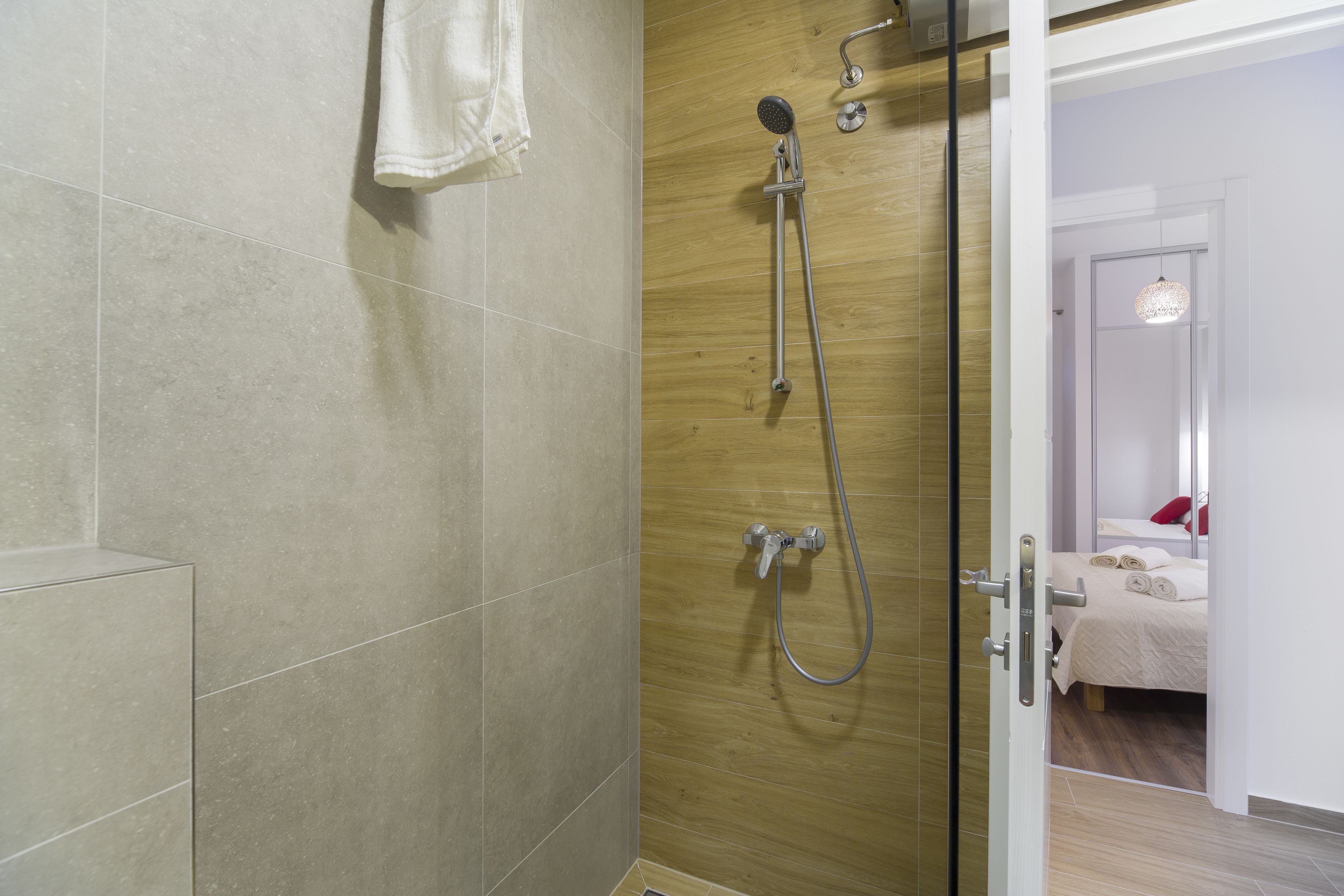A shower with a handheld showerhead and a wall-mounted faucet.