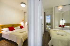Une chambre d’hôtel avec deux lits, une tête de lit en bois, un balcon avec vue et un grand miroir.