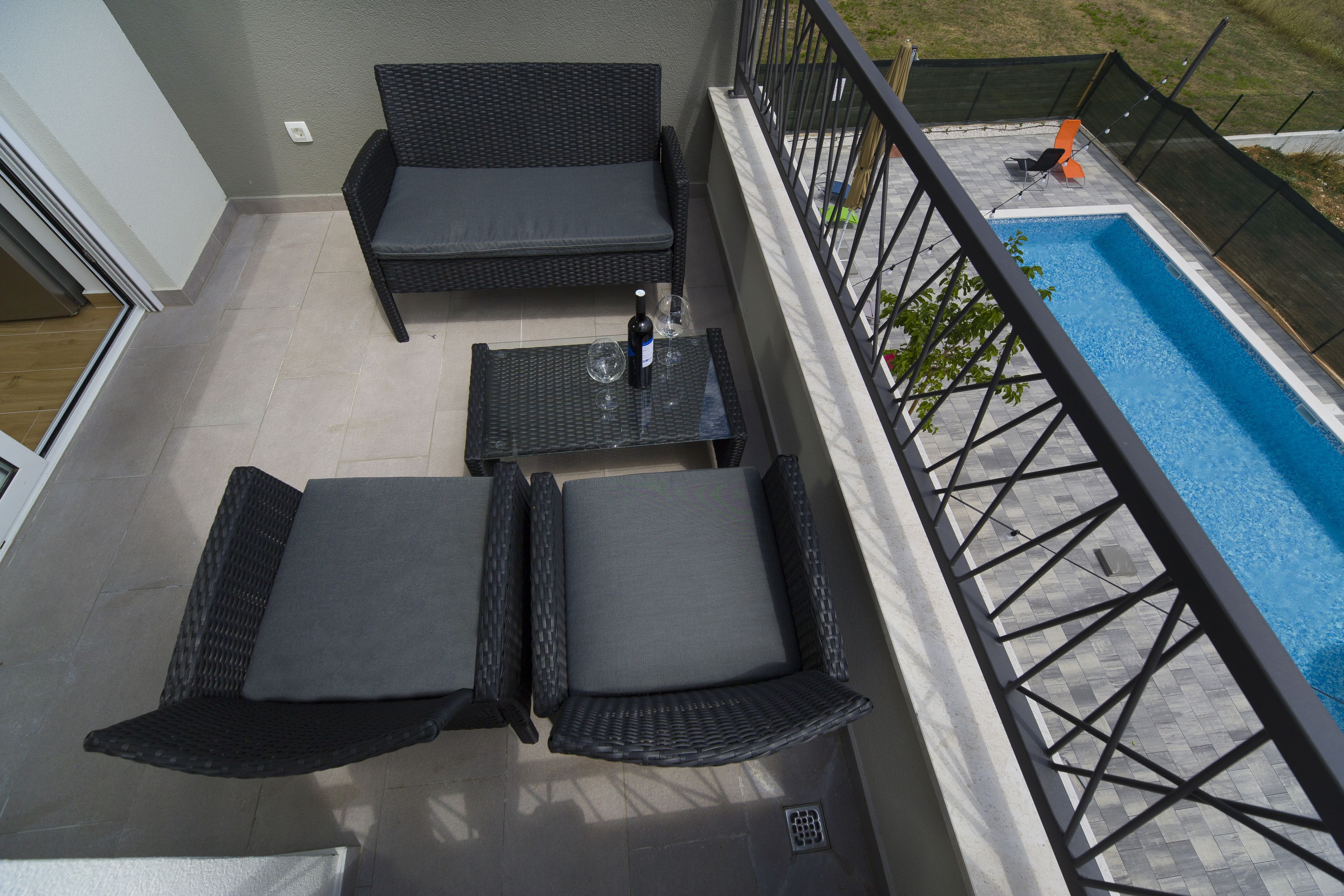 Un balcón con mobiliario de mimbre, una piscina y vistas al exterior.