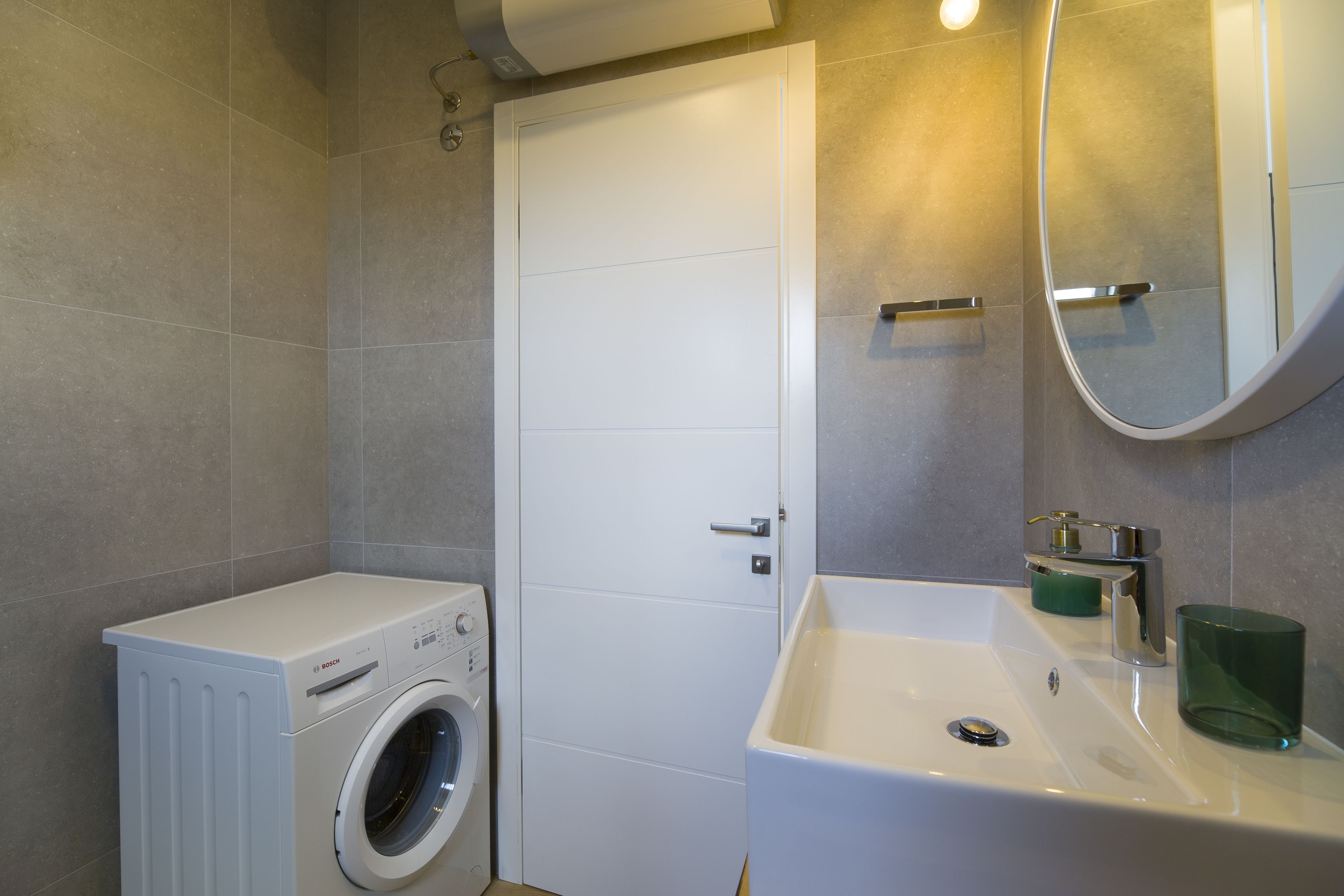 Un baño moderno con lavadora integrada, un lavabo y un espejo.