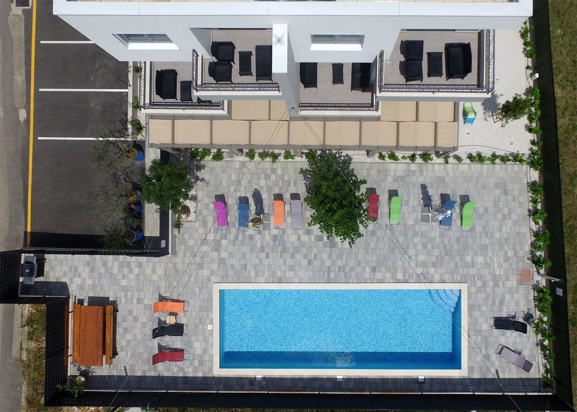 Un área de piscina en la azotea con piscina rectangular, sillas de descanso y zona de comedor.