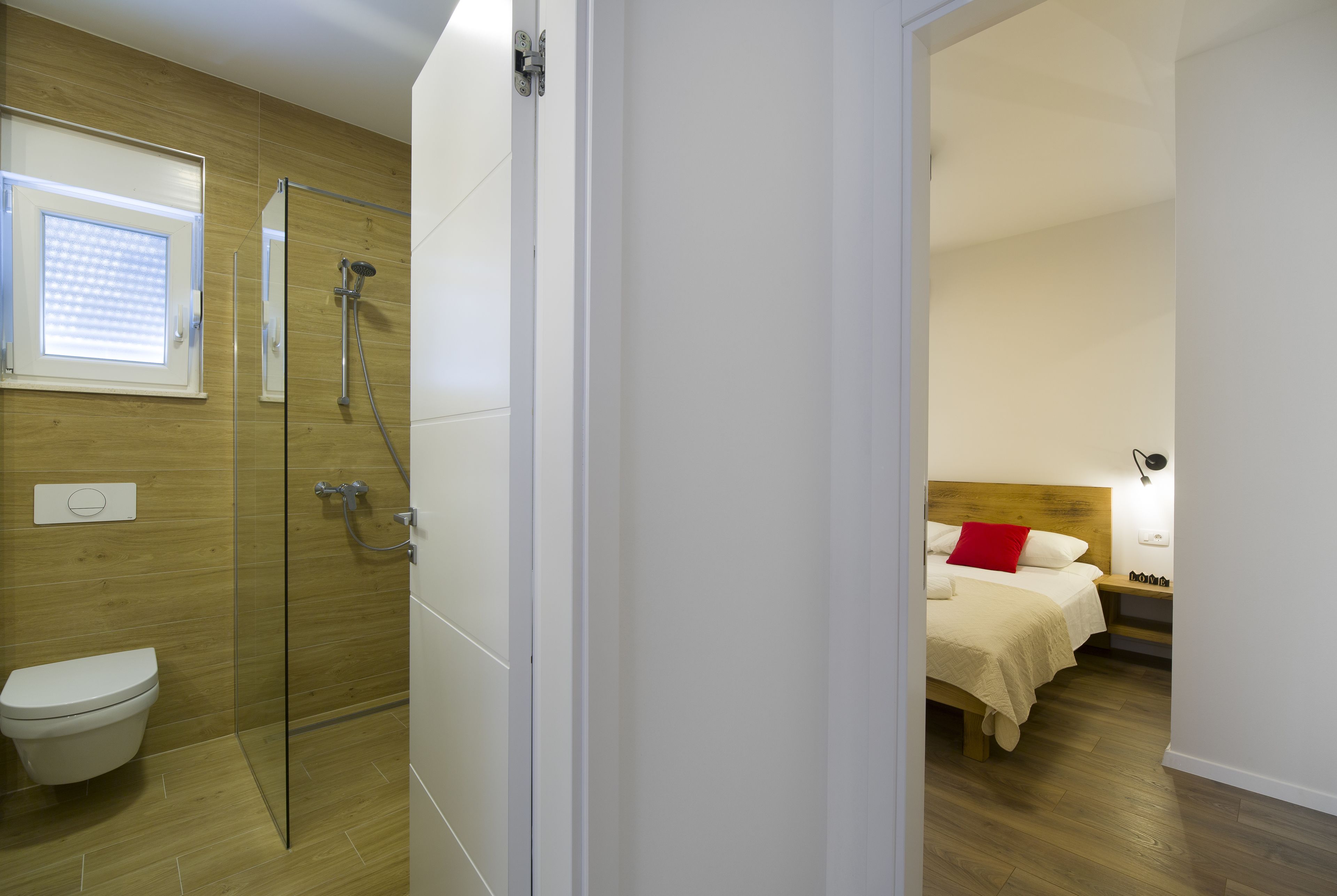 Une salle de bain moderne avec une douche à parois de verre, des toilettes et un plancher en bois.