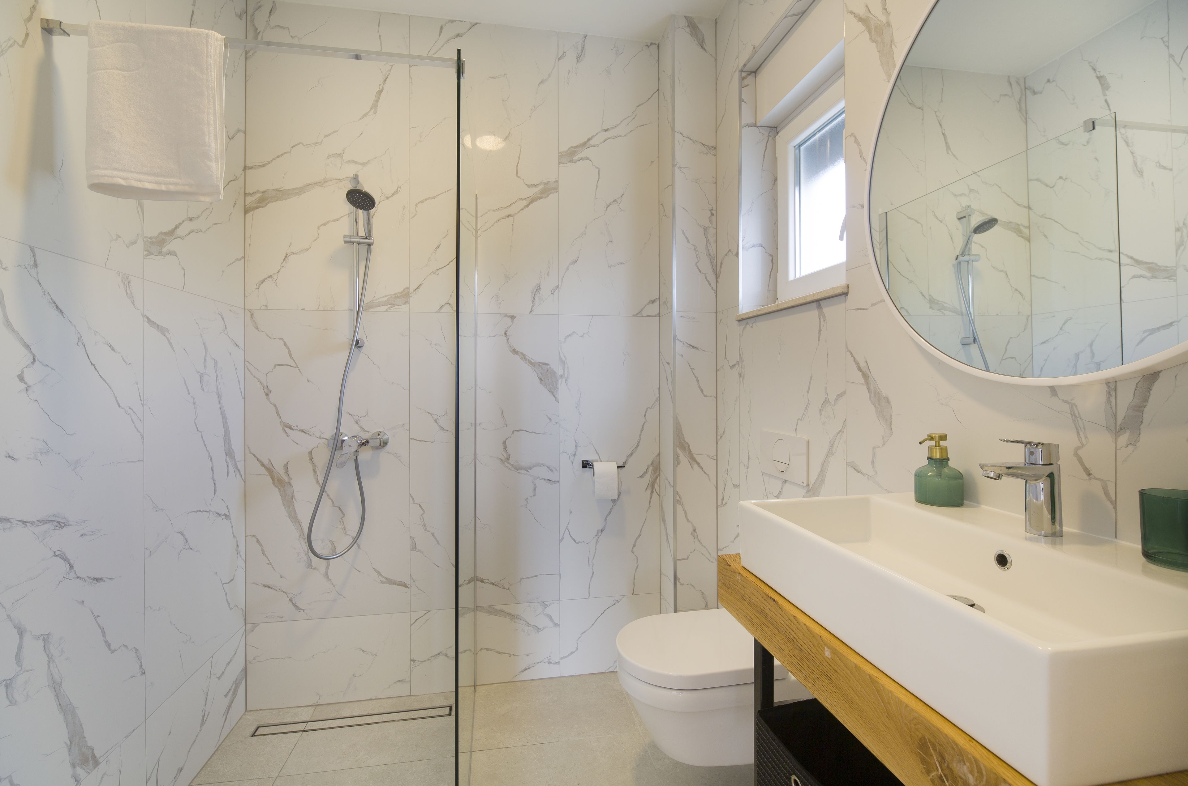 A bathroom with a glass-enclosed shower, a white toilet, and a sink with a mirror above it.