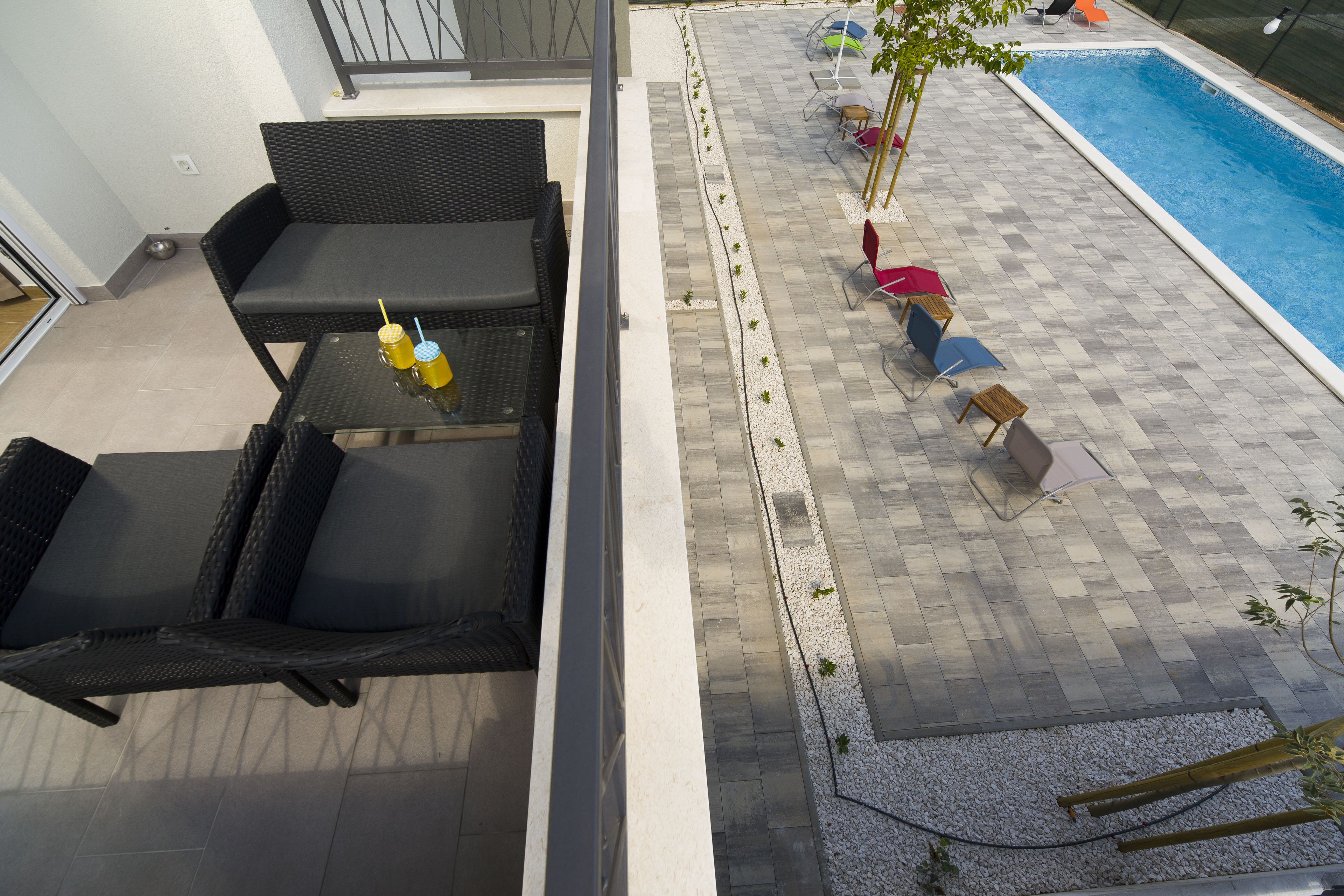 An outdoor area with a pool, seating, and a small table with drinks.
