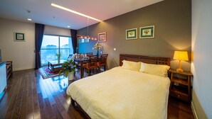 Een hotelkamer met een groot bed, een eettafel met stoelen, een kitchenette en uitzicht op de stad.