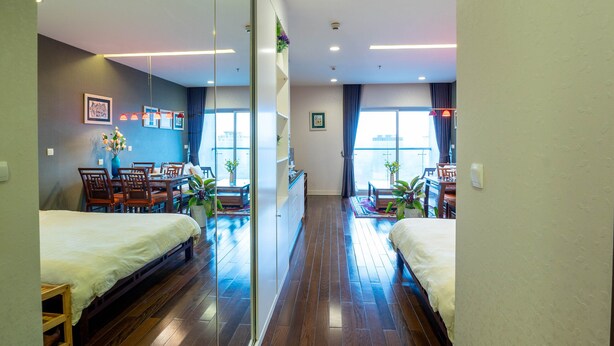 Een hotelkamer met houten vloer, een bed, een bureau en een stoel.