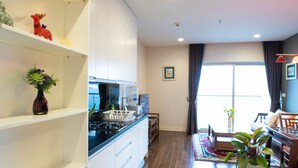 Een moderne keuken met witte kasten, een ingebouwde kookplaat en een waterdispenser. Er is een eethoek met een tafel en stoelen, en een groot raam met gordijnen.