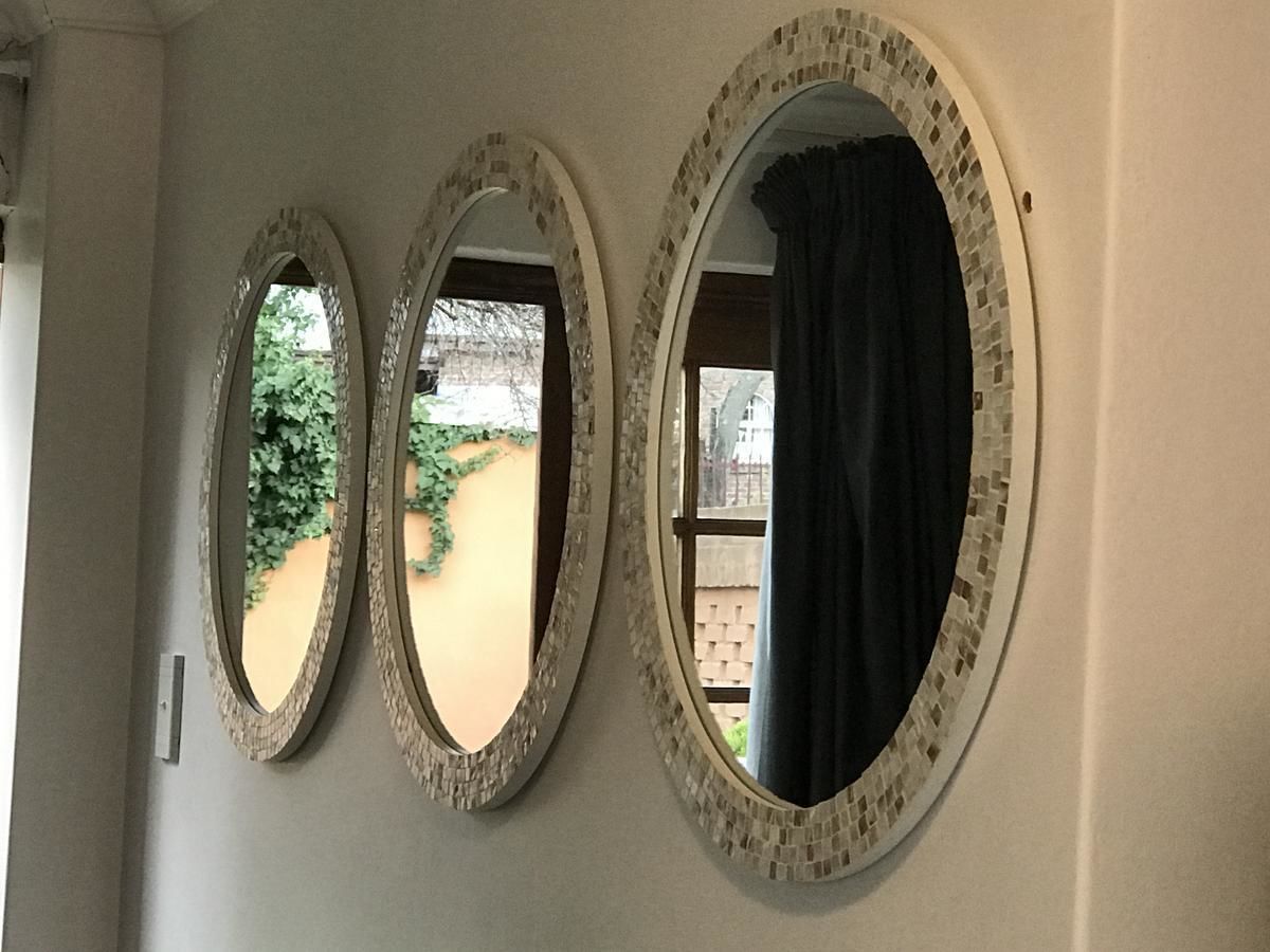 Three oval mirrors with mosaic frames on a wall.